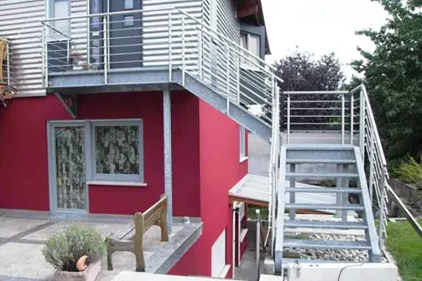 Geländer_neu Außentreppe mit Metallgeländer an roter Hausfassade